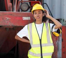 retrato do engenheiro industrial mulher multirracial no capacete trabalhando no armazém de contêineres logísticos. inspetor ou supervisor em colete de segurança é responsável pelo armazenamento de carga e comércio global de entrega foto