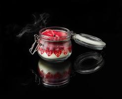 uma vela apagada com fumaça em fundo preto com aromas de baunilha, cereja, romã e coco