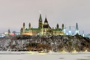 colina do parlamento e a casa do parlamento canadense em ottawa, canadá durante o inverno à noite. foto