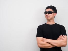 homem asiático usando óculos de sol cruzando o braço e olhando para o espaço da cópia foto