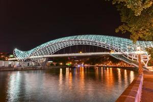 a ponte da paz em tbilisi, uma ponte pedonal sobre o rio mtkvari em tbilisi, geórgia iluminada à noite. foto