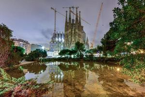 la sagrada familia iluminada à noite, refletindo na água. a catedral foi projetada por antoni gaudi e está em construção desde 1882 em barcelona, espanha, 2022 foto