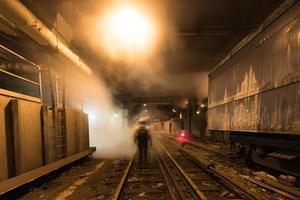 trabalhador atravessando os trilhos do trem subterrâneo da grande estação central na cidade de nova york. foto