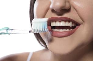 retrato de uma mulher sorridente atraente isolada em um tiro de estúdio branco escovando os dentes foto