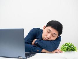 homem asiático dorme com seu laptop na mesa tentou trabalhar em casa foto