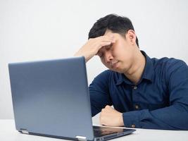 funcionário do sexo masculino sente-se com o laptop sentindo-se tentado e com dor de cabeça com o trabalho foto