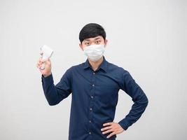 homem asiático usando máscara segurando o termômetro infravermelho para escanear o fundo branco do retrato foto