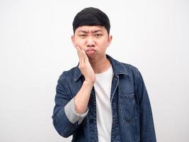 camisa jeans de homem asiático sentindo dor de dente tocar sua bochecha foto