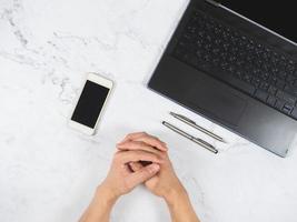 espaço de trabalho na mão da mesa de mármore com caneta para celular e vista superior do laptop foto