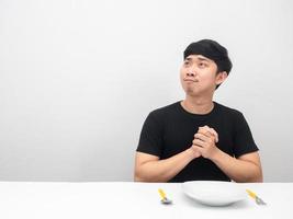 homem segurando talheres sentado à mesa sentindo-se feliz e olhando para o espaço da cópia foto