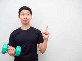 homem asiático segurando drumbbell rosto feliz dedo apontado na motivação do espaço de cópia para o conceito de treino foto