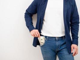 homem de close-up pega dinheiro do bolso de jeans no conceito rico de fundo branco foto