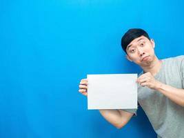 homem asiático mostra lençol branco vazio na mão fundo azul foto