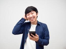 homem tímido toca sua cabeça e segurando o telefone móvel rosto sorriso fundo branco foto