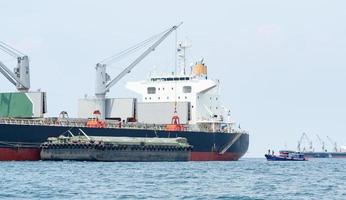 guindaste no navio industrial na água azul do oceano e paisagem de céu azul, logística e conceito de navio de transporte no mar foto