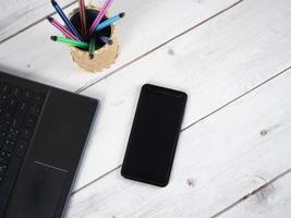 espaço de trabalho na mesa, caixa de caneta para laptop e vista superior do celular foto