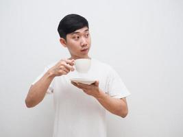 homem asiático segura a xícara de café na mão e olha para o lado direito com um sorriso feliz no fundo branco isolado foto