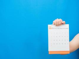 mão de homem segurando calendário 2022 em fundo azul foto