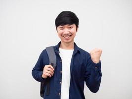 jovem com mochila escolar rosto sorridente mostra punho para cima feliz emoção retrato fundo branco foto