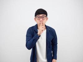 homem asiático com classes dedo na boca conceito shh em fundo branco isolado foto
