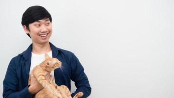homem asiático alegre carrega gato olhando para o espaço fundo branco