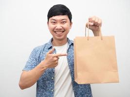 homem retrato sorrindo apontar o dedo na sacola de compras na mão foto