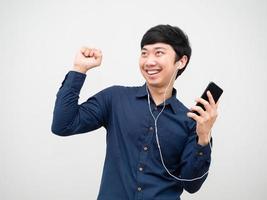 homem asiático ouvindo música pelo fone de ouvido segurando o celular e dançando diversão em emoção feliz foto