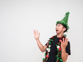 homem asiático camisa preta com chapéu verde e borla colorida alegre no rosto mostra a mão para cima e olha para cima na celebração de fundo branco feliz conceito de ano novo