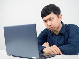 funcionário do sexo masculino sentado na área de trabalho do escritório emoção séria olhando para laptop foto