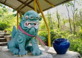 uma velha estátua de leão verde chinês amarrada com um laço tricolor no peito. seu nome chinês é chamado pixiu ou pi yao. foto