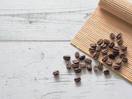 grupo de sementes de café na placa de bambu vista superior no espaço da mesa de madeira