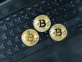 três bitcoins dourados no teclado do laptop cor preta o conceito de criptomoeda de dinheiro digital foto