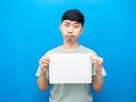 homem segurando papel vazio branco dúvida emoção fundo azul foto