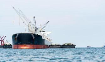 guindaste no navio industrial na água azul do oceano e paisagem de céu azul, logística e conceito de navio de transporte no mar foto