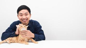 homem asiático sorrindo com seu gato na mesa copie o espaço fundo branco foto