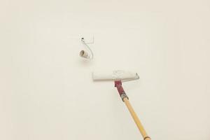 parede de pintura de mão masculina com rolo de pintura. apartamento de pintura, reformando com tinta na cor branca. reformas de quartos em casa. foto