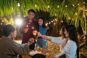 jovens festeiros alegremente seguram brilhos em comemoração foto