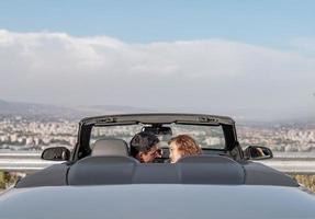 amigos se divertindo na viagem de carro ao redor do mundo. casal apaixonado com os braços para cima em um carro conversível. foto