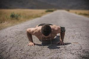 atleta masculino exercitando push up lá fora sob o sol ensolarado. ajuste o modelo de fitness masculino sem camisa em exercícios crossfit ao ar livre. conceito de estilo de vida saudável. foto