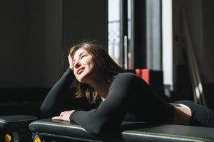 retrato de uma jovem morena descansando em roupas esportivas no ginásio do clube de fitness foto