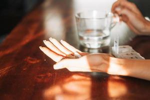 mãos femininas com ômega 3, cápsulas de vitamina d com copo de água foto