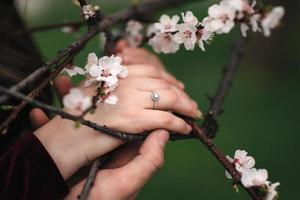 mãos de um jovem casal com um anel. conceito de amor, casal, relacionamento e férias - close-up do homem dando um anel de diamante para a mulher foto