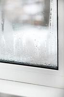 uma janela de plástico com condensação de água no vidro. janela em pvc com vidro duplo. janela de plástico com defeito de conceito com condensação, diferença de temperatura, resfriamento, umidade na sala. foto