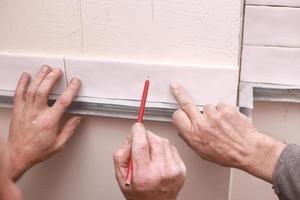 elegantes azulejos brancos na moda na parede da cozinha. mãos no processo de colocação de azulejos retangulares brancos na parede do banheiro. reforma de apartamentos e banheiros. foto