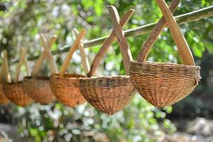 cesta de vime pendurada na vara de bambu foto