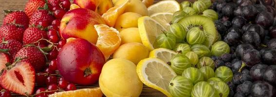 bagas frescas e frutas em um fundo de madeira. cor do arco-íris. o conceito de alimentação saudável. A vista do topo foto