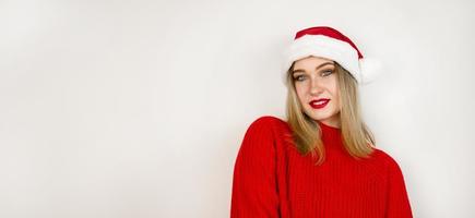banner de natal de dezembro com espaço de cópia. jovem loira feliz sorrindo vestindo suéter vermelho e chapéu de Papai Noel foto