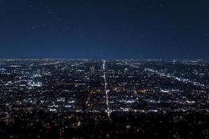 tiro de drone de paisagem urbana iluminada e belas estrelas brilhando no céu escuro foto