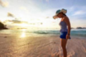 mulher de imagem borrada na praia ao nascer do sol foto