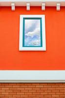 reflexo do céu no vidro da janela na parede laranja foto